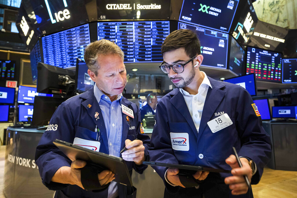 In this photo provided by the New York Stock Exchange, traders Robert Charmak, left, and Orel Partush confer on the floor, Thursday, March 24, 2022. Stocks edged higher in morning trading on Wall Street as a streak of cautious trading continues on world markets.