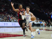 Oklahoma City Thunder forward Isaiah Roby, right, dribbles past Portland Trail Blazers forward Elijah Hughes during the second half of an NBA basketball game in Portland, Ore., Monday, March 28, 2022.