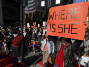 FILE - Dennis Willard, of Bellevue, Wash., carries a sign that reads "Where Is She" as he marches in support of missing and murdered indigenous women during a rally to mark Indigenous Peoples' Day in downtown Seattle, on Oct. 14, 2019. Washington Gov. Jay Inslee has signed into law a bill that creates a first-in-the-nation statewide alert system for missing Indigenous people. The law creates a system similar to Amber Alerts and so-called silver alerts, which are used respectively for missing children and vulnerable adults in many states. (AP Photo/Ted S.