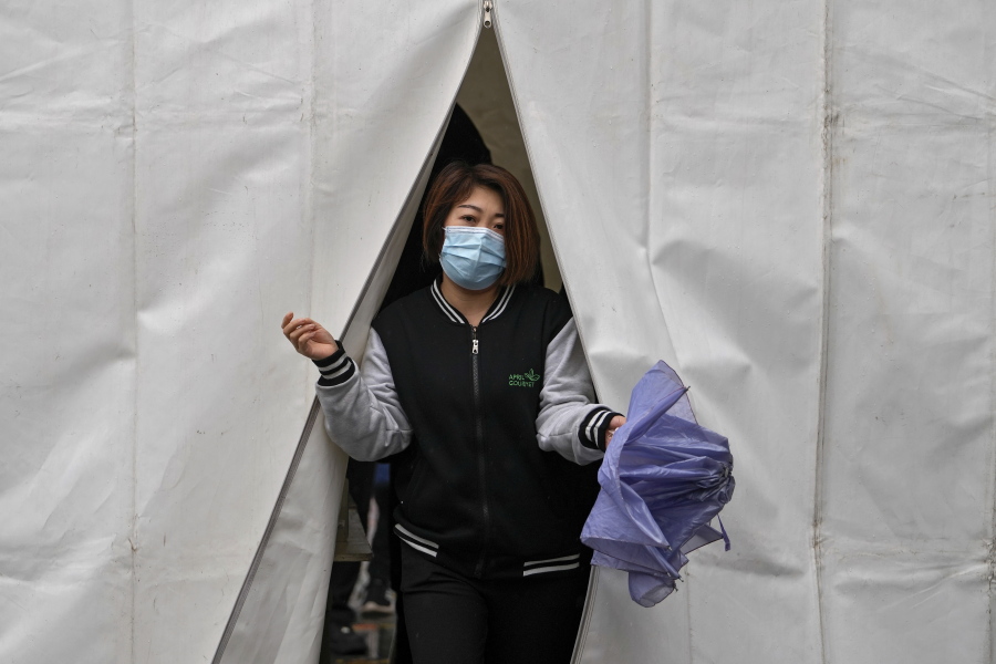 A woman wearing a face mask to help protect from the coronavirus walks out from a tent after getting a COVID-19 test, Tuesday, March 29, 2022, in Beijing. A two-phase lockdown of Shanghai's 26 million people is testing the limits of China's hard-line "zero-COVID" strategy, which is shaking markets far beyond the country's borders.