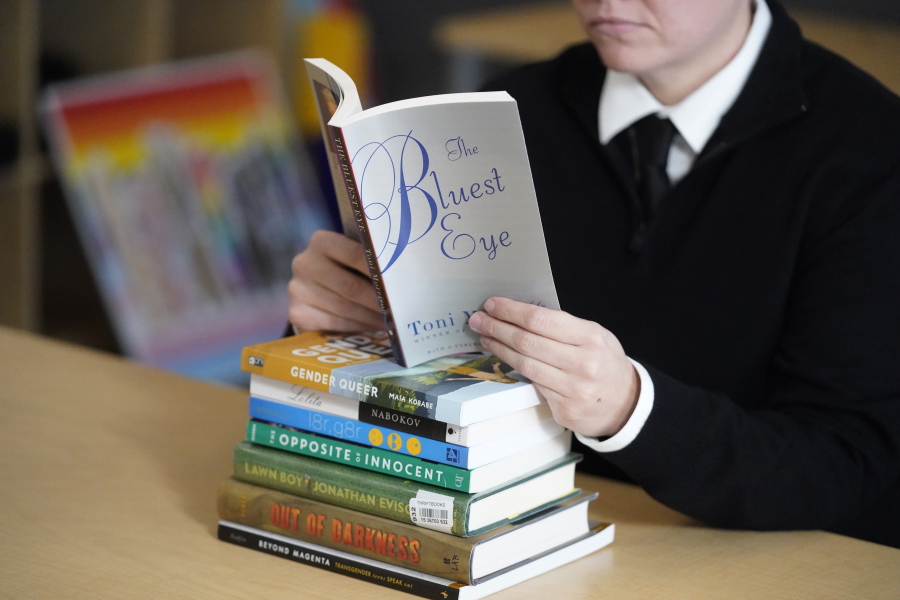 FILE - Amanda Darrow, director of youth, family and education programs at the Utah Pride Center, poses with books, including "The Bluest Eye," by Toni Morrison, that have been the subject of complaints from parents in Salt Lake City on Dec. 16, 2021. The wave of book bannings around the country has reached a level not seen for decades.