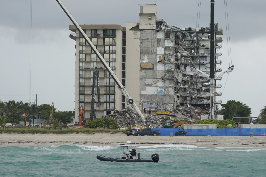 FILE - A Florida Fish and Wildlife Conservation law enforcement boat patrols in the ocean in front of search and rescue efforts at the Champlain Towers South condo building, where scores of people remain missing almost a week after it partially collapsed, Wednesday, June 30, 2021, in Surfside, Fla. People who owned units in a Florida oceanfront condominium building that collapsed last year will divide $83 million for property losses, with the compensation for families over the 98 deaths still to be determined. Miami-Dade Circuit Judge Michael Hanzman approved the deal Wednesday, March 30, 2022.