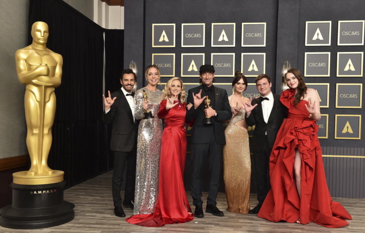FILE - Eugenio Derbez, from left, Sian Heder, Marlee Matlin, Troy Kotsur, Emilia Jones, Daniel Durant and Amy Forsyth, winners of the award for best picture for "CODA," pose in the press room while signing "I love you" at the Oscars on March 27, 2022, at the Dolby Theatre in Los Angeles. The three Oscar wins for the film "CODA" has provided an unprecedented feeling of affirmation to people in the Deaf community.