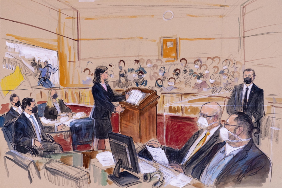 This artist sketch depicts Guy Wesley Reffitt, bottom right, joined by his lawyer William Welch, third from right, listening as prosecutor Risa Berkower, speaks at the podium at center, as a video depicts a handgun on the waist of Reffitt, at left, for members of the jury and audience in Federal Court, in Washington, Monday, March 7, 2022. Reffitt, a Texas man charged with storming the U.S. Capitol with a holstered handgun on his waist, is the first Jan. 6 defendant to go on trial. Also pictured from left, are prosecutors Tom Ryan, Jeff Nestler, and Amanda Rohde.