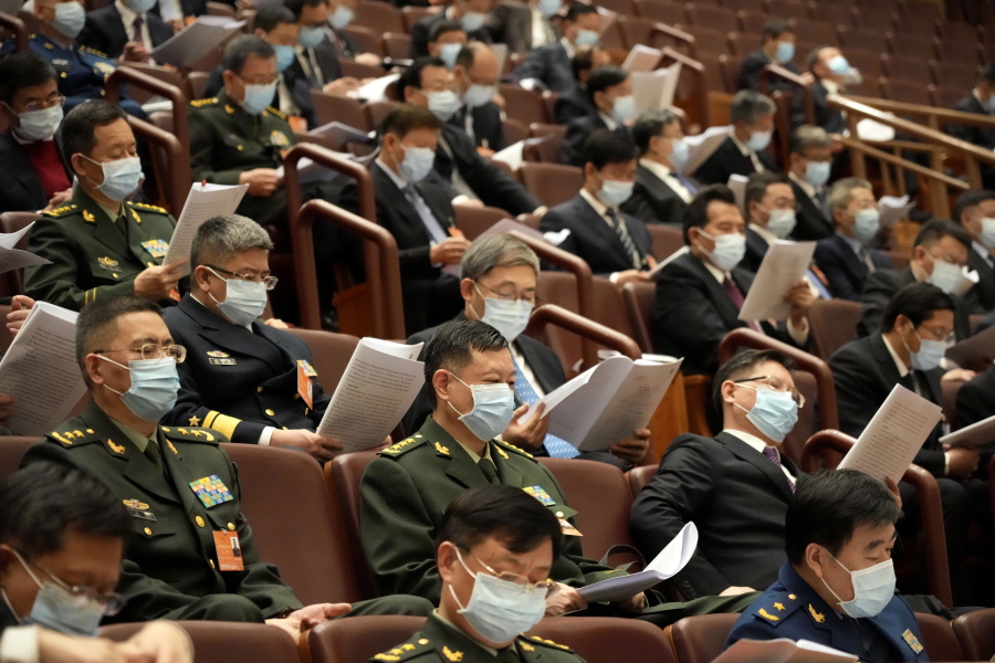 Attendees look at documents during the opening session of the annual meeting of China's National People's Congress (NPC) at the Great Hall of the People in Beijing, Saturday, March 5, 2022.