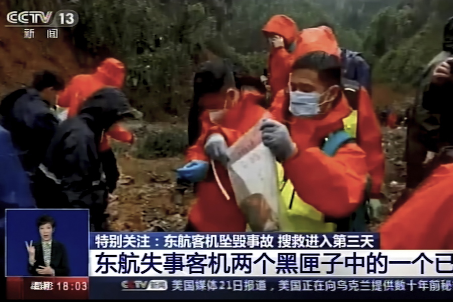 In this image taken from video footage run by China's CCTV, an emergency worker puts an orange-colored "black box" recorder into a plastic bag at the China Eastern flight crash site Wednesday, March 23, 2022, in Tengxian County in southern China's Guangxi Zhuang Autonomous Region. A Chinese aviation official said Wednesday that one of the two "black box" recorders had been found in severely damaged condition, two days after a China Eastern flight crashed in southern China with 132 people on board.