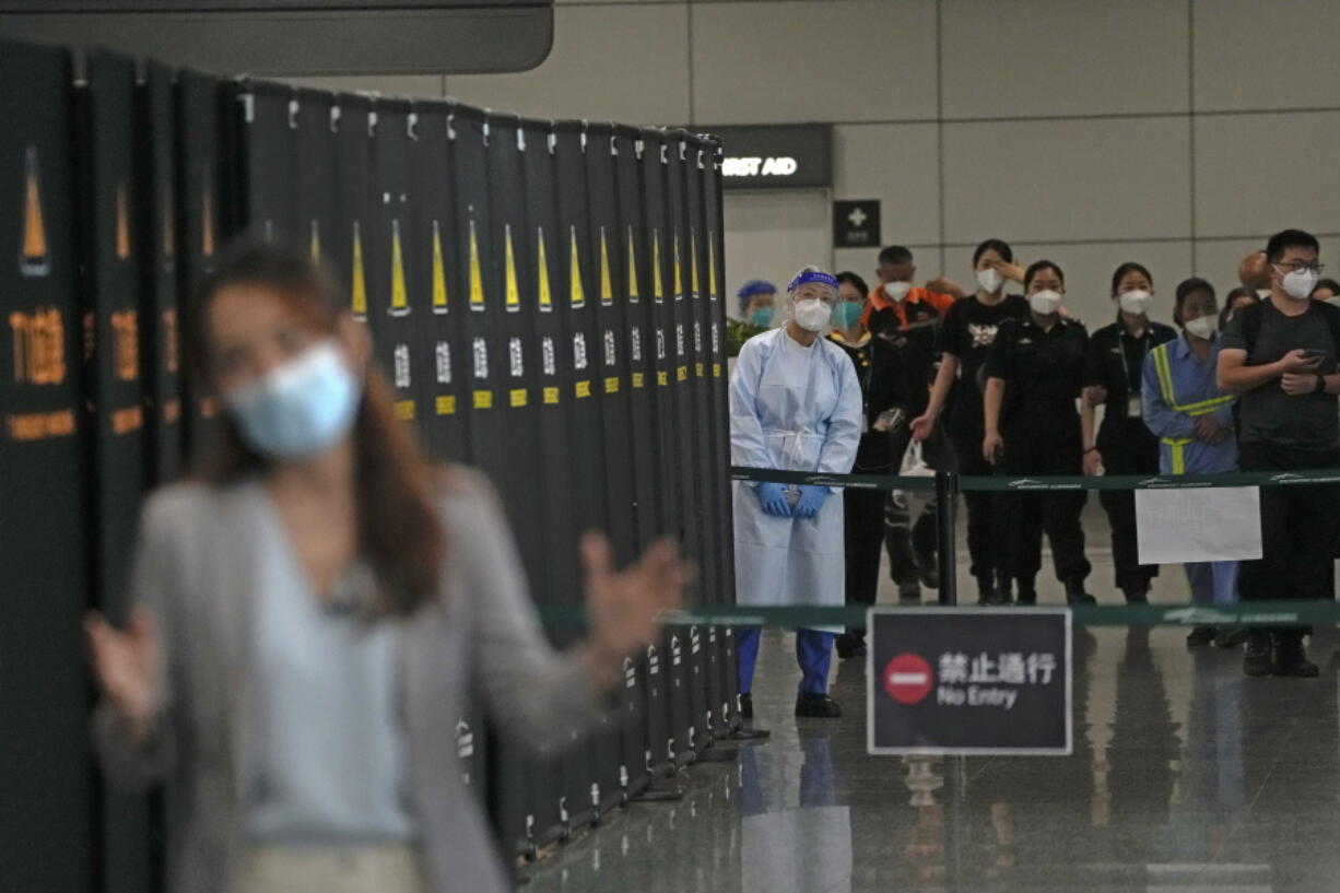 Workers and security personnel talk with a journalist reporting near a cordoned off area for the relatives of victims aboard China Eastern's flight MU5735, in the Guangzhou Baiyun International Airport in Guangzhou, capital of south China's Guangdong Province, Tuesday, March 22, 2022. No survivors have been found as rescuers on Tuesday searched the scattered wreckage of a China Eastern plane carrying 132 people that crashed a day earlier on a wooded mountainside in China's worst air disaster in more than a decade.