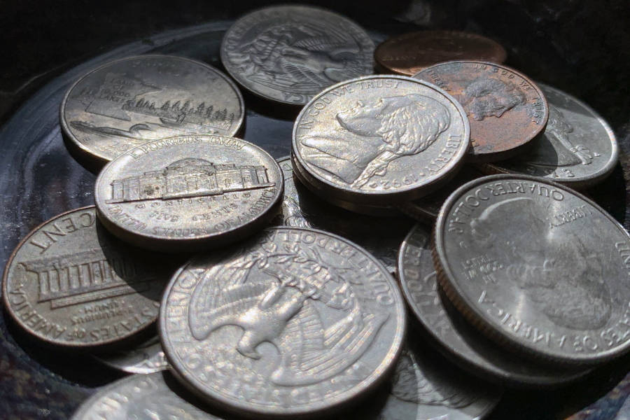 Quarters, nickels, dimes and pennies are held a bowl Thursday, March 31, 2022, in Tigard, Ore.