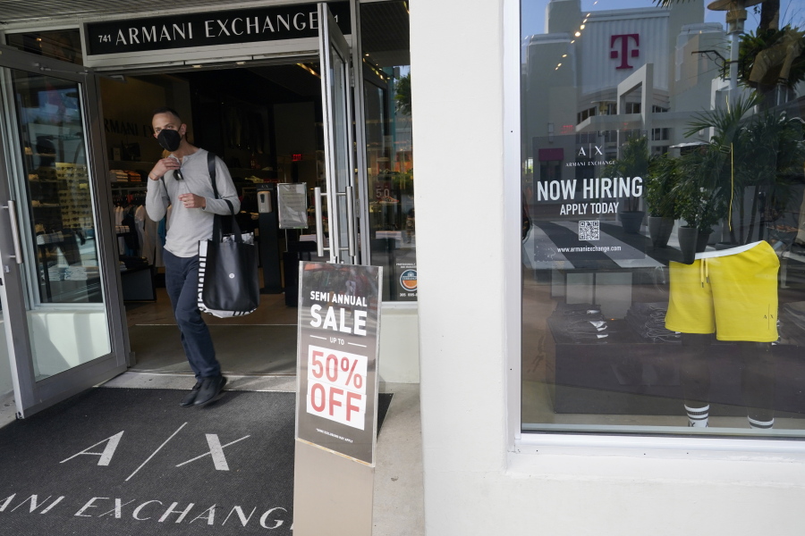 For sale and hiring signs are displayed at an Armani Exchange store, Friday, Jan. 21, 2022, in Miami Beach, Fla.