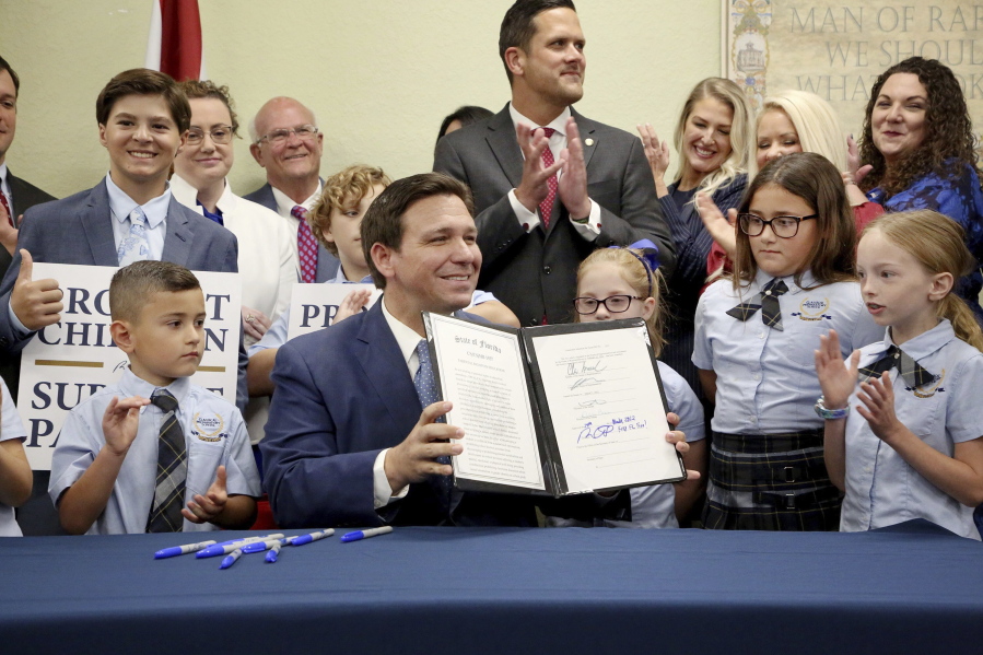 Florida Gov. Ron DeSantis displays the signed Parental Rights in Education, aka the Don't Say Gay bill, flanked by elementary school students during a news conference on Monday, March 28, 2022, at Classical Preparatory school in Shady Hills. (Douglas R.