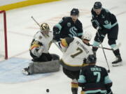 Vegas Golden Knights goaltender Logan Thompson deflects a shot as Seattle Kraken left wing Jared McCann, upper-center, and center Ryan Donato (9) look on during the second period of an NHL hockey game, Wednesday, March 30, 2022, in Seattle. (AP Photo/Ted S.