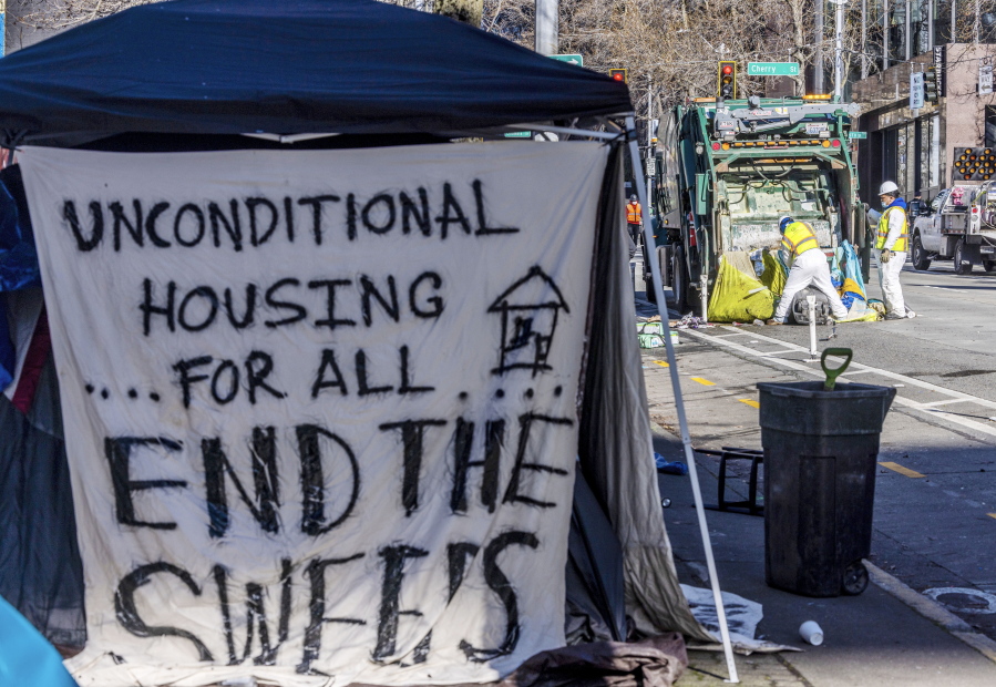 A sign on a shelter reads "Unconditional Housing for All End the Sweeps" as city of Seattle workers remove tents, trash, and personal belongings from a stretch of sidewalk across from City Hall that had been used by people experiencing homelessness, on March 9, 2022, in Seattle. For years, liberal cities in the U.S have tolerated people living in tents in parks and public spaces, but increasingly leaders in places like Portland, Oregon, New York and Seattle are removing encampments and pushing other strict measures that would've been unheard of a few years ago.