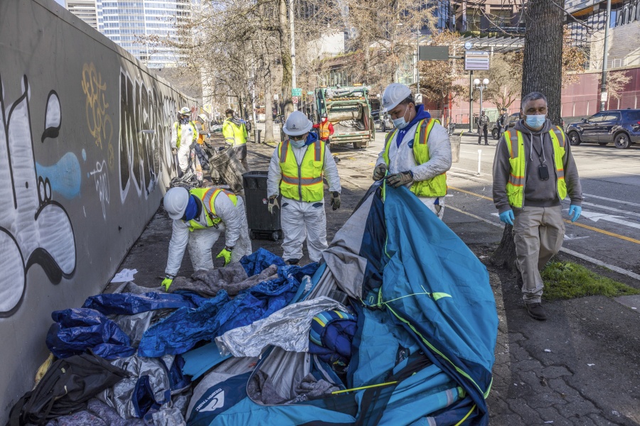 City of Seattle workers remove tents, trash, and personal belongings from a stretch of sidewalk across from City Hall that had been used by people experiencing homelessness, on March 9, 2022, in Seattle. For years, liberal cities in the U.S have tolerated people living in tents in parks and public spaces, but increasingly leaders in places like Portland, Oregon, New York and Seattle are removing encampments and pushing other strict measures that would've been unheard of a few years ago.