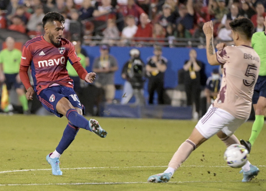 FC Dallas forward Jesus Ferreira (10) scores his third goal of an MLS soccer match between the legs of Portland Timbers defender Claudio Bravo (5) in the first half Saturday, March 19, 2022, in Frisco, Texas.