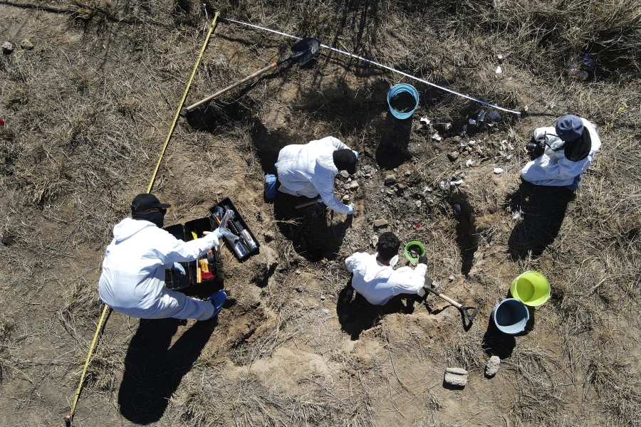 Forensic technicians excavate a field on a plot of land referred to as a cartel "extermination site" where burned human remains are buried, on the outskirts of Nuevo Laredo, Mexico, Tuesday, Feb. 8, 2022. The  insufficiency of investigations into Mexico's nearly 100,000 disappearances is evident. There are 52,000 unidentified people in morgues and cemeteries, not counting places like this one, where the charred remains are measured only by weight.