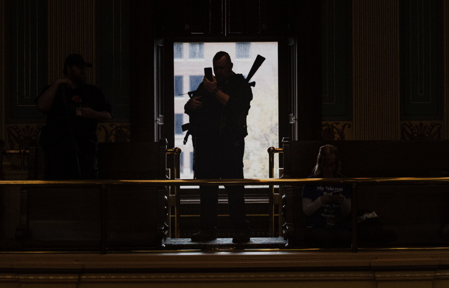 Militia members wait inside the Senate chamber at the Capitol building during the "American Patriot Rally on Capitol Lawn" protest in Lansing, Mich., Thursday April 30, 2020, during the coronavirus outbreak. Experts say far-right groups in the U.S. are taking a more dangerously radical turn as four men go on trial in an alleged scheme to kidnap Michigan's governor.