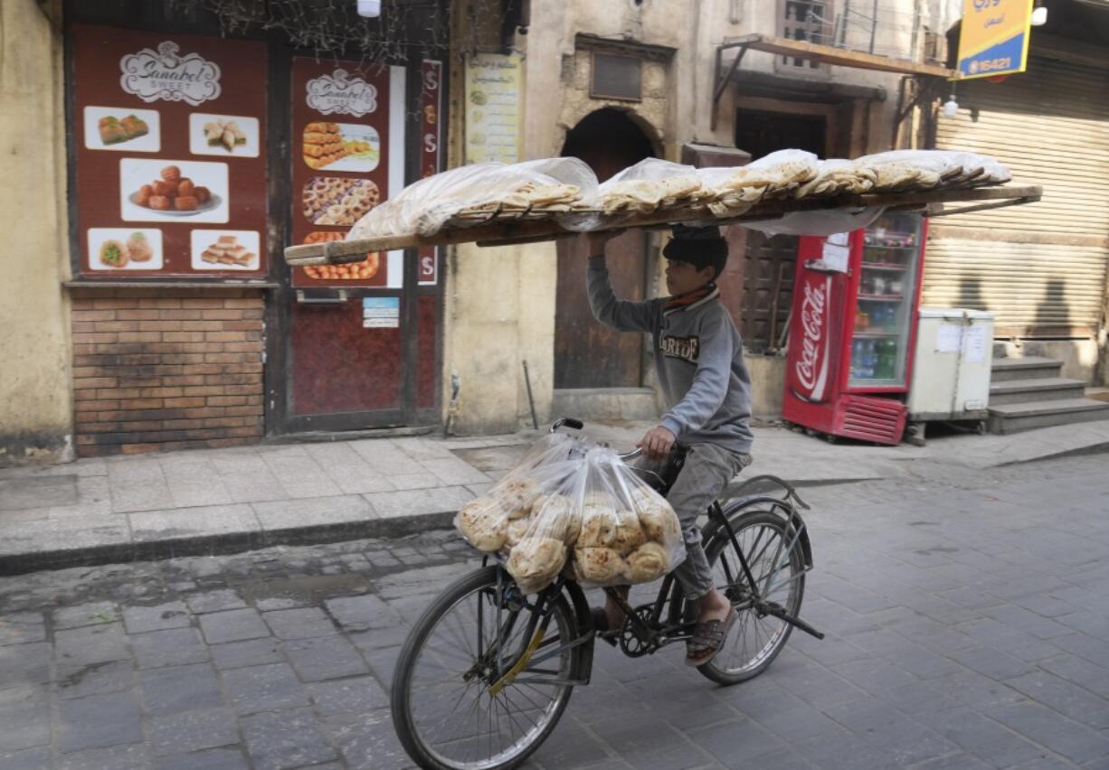 A vendor balances a tray of Egyptian traditional "Baladi" flatbread as he cycles in Old Cairo district, Egypt, Tuesday, March 22, 2022. Experts say they are worried that food security concerns in the Middle East resulting from the war in Ukraine may fuel growing social unrest in countries already on the verge of meltdown.