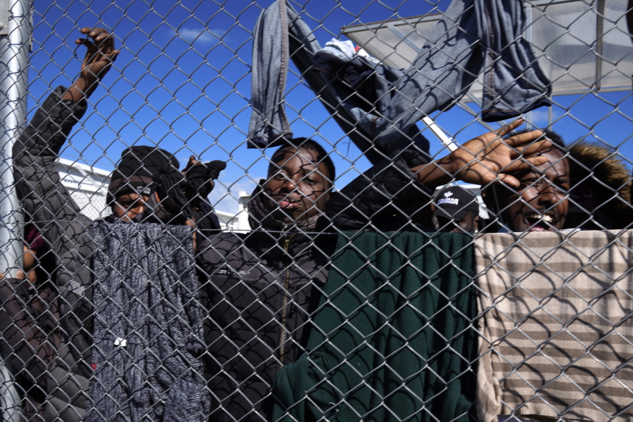 Migrants stand behind a fence during Cyprus' president Nicos Anastasiades visit the Pournara migrant reception center in Kokkinotrimithia outside of capital Nicosia, Cyprus, on Monday, March 14, 2022.