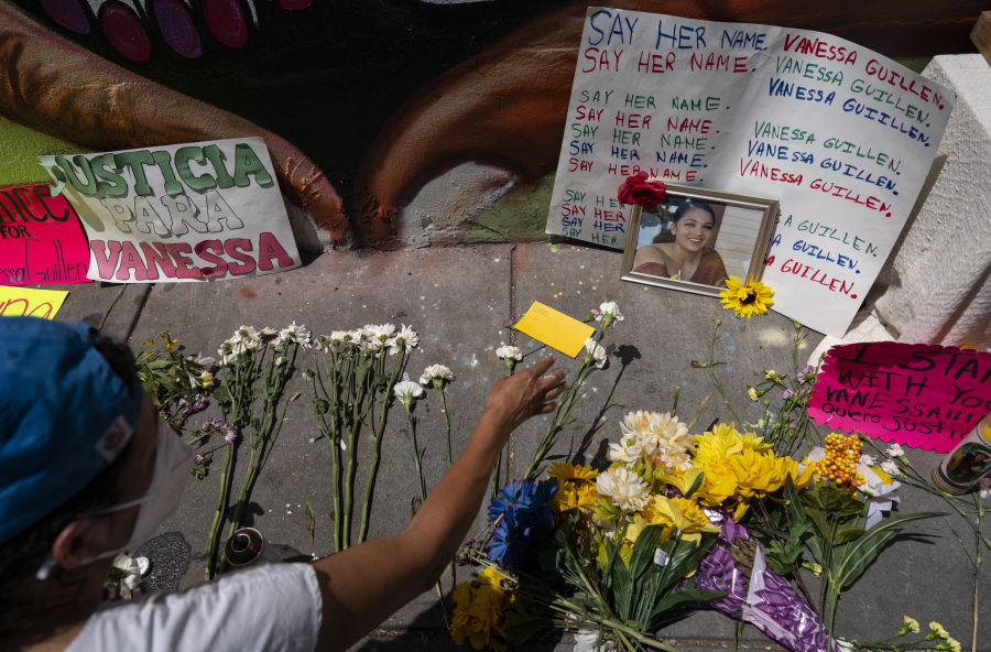FILE - Frida Larios places flowers near of photograph of slain Army Spc. Vanessa Guillen at the base of a mural of Guillen on 14th Street NW in Washington, July 13, 2020. Guillen was killed by a soldier, who her family says sexually harassed her, and who killed himself as police sought to arrest him.