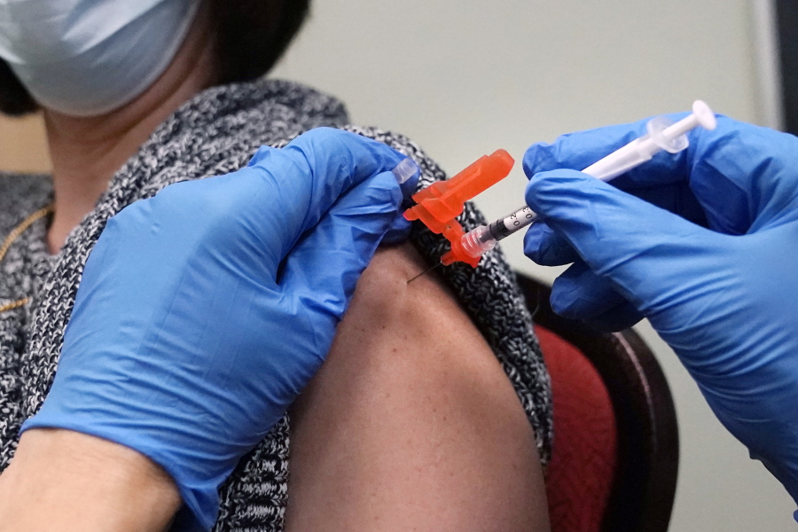 FILE - A woman receives a COVID-19 vaccine injection by a pharmacist at a clinic in Lawrence, Mass., on Wednesday, Dec. 29, 2021.   On Friday, March 11, 2022, The Associated Press reported on stories circulating online incorrectly claiming people who have received COVID-19 vaccine booster shots are at a greater risk of dying from the virus.