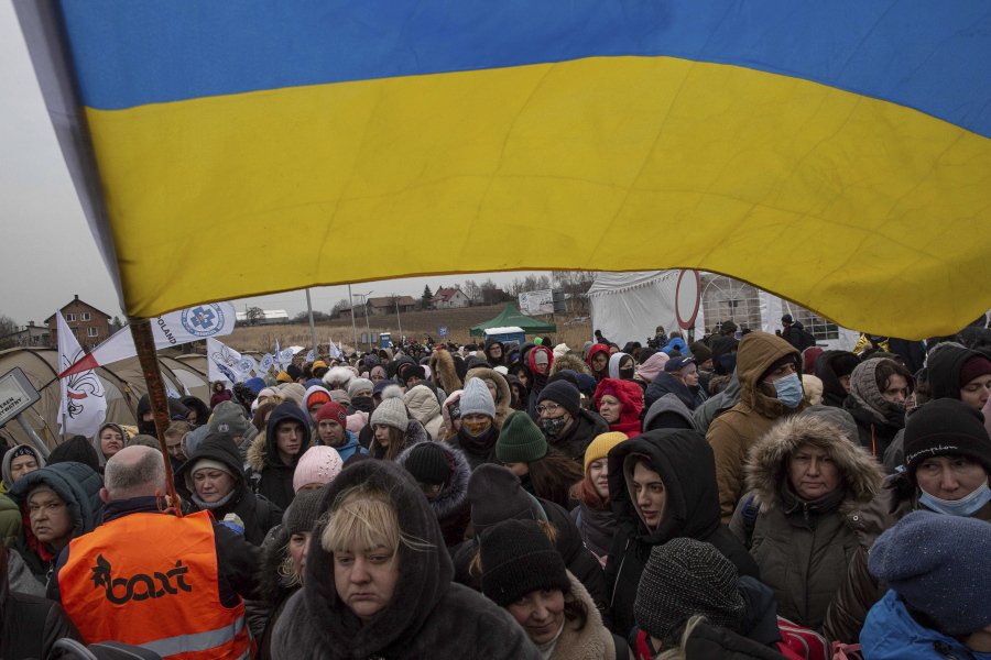 A Ukrainian volunteer Oleksandr Osetynskyi, 44 holds a Ukrainian flag and directs hundreds of refugees after fleeing from the Ukraine and arriving at the border crossing in Medyka, Poland, Monday, March 7, 2022. Russia announced yet another cease-fire and a handful of humanitarian corridors to allow civilians to flee Ukraine. Previous such measures have fallen apart and Moscow's armed forces continued to pummel some Ukrainian cities with rockets Monday.