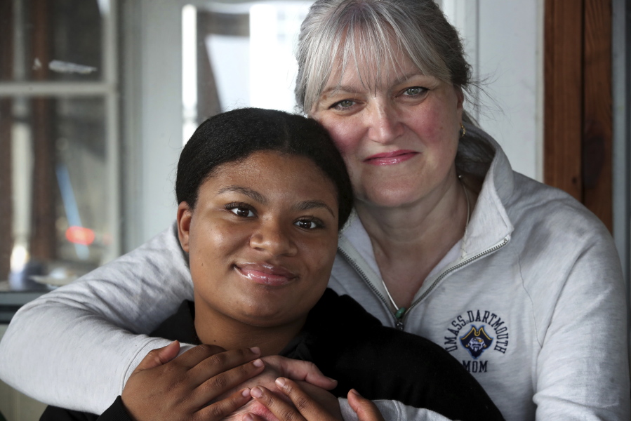 Deanna Cook, left, poses for a photograph with her mother Colleen at their home in Malden, Mass., Tuesday, March 15, 2022. A bill aimed at banning race-based discrimination targeting hair texture and hairstyles was unanimously approved Thursday, March 17, 2022 by the Massachusetts House. The issue came to light when the parents of then-15-year-old Black girls, Deanna and Mya Cook, said their twin daughters were punished for wearing extensions, while white students hadn't been punished for violations of hairstyle regulations, including coloring their hair. (Craig F.