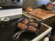 Mule deer backstrap steaks are seen cooking in Jaden Bales' kitchen south of Lander, Wyoming, on Thursday, March 3, 2022. Bales collected the deer after Lander resident Marta Casey accidentally hit it with her car. Bales used a new state of Wyoming mobile app for claiming road-killed animals to eat. The app may be the first of its kind in the U.S.