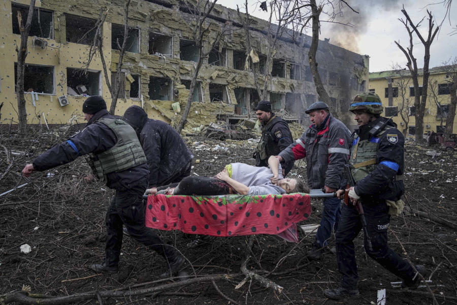 FILE - Ukrainian emergency employees and volunteers carry an injured pregnant woman from a maternity hospital that was damaged by shelling in Mariupol, Ukraine, March 9, 2022. The woman and her baby died after Russia bombed the maternity hospital where she was meant to give birth.