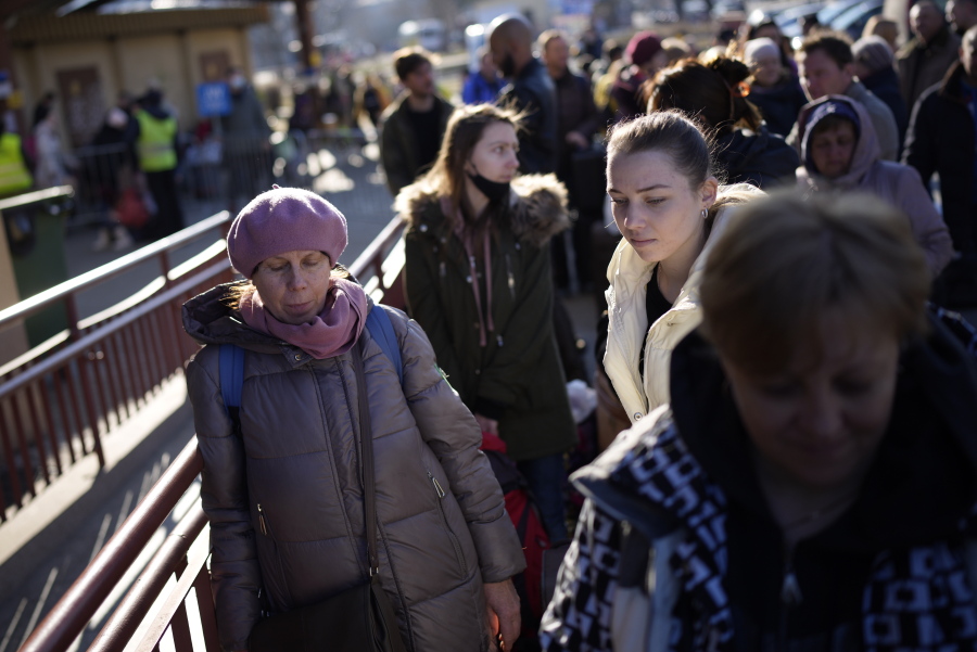 People wait in a line to board a train leaving for Lviv in Ukraine at the train station in Przemysl, Poland, Monday, March 14, 2022. While tens of thousands of people have fled Ukraine every day since Russia's invasion, a small but growing number are heading in the other direction. At first they were foreign volunteers, Ukrainian expatriate men heading to fight and people delivering aid. But increasingly, women are also heading back.
