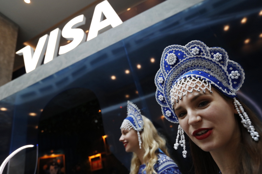 FILE - In this July 5, 2018 photo, women wearing traditional head dresses wait to greet Visa cardholders who won trips to the 2018 soccer World Cup, at the Marriott Novy Arbat Hotel, taken over by visa for the duration of the World Cup in Moscow, Russia. Mastercard and Visa are suspending their operations in Russia, the companies said Saturday, March 5, 2022, in the latest blow to the country's financial system after its invasion of Ukraine.