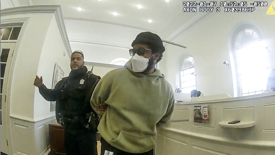 A police officer detains "Black Panther" director Ryan Coogler at a Bank of America branch in Atlanta, in this January 2022 image made from Atlanta Police video. Coogler was mistaken for a bank robber at the bank.