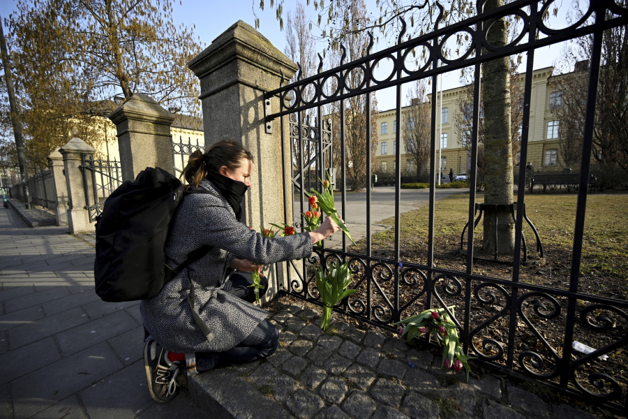 Katarina Blennow lays flowers outside Malmo Latin School in Malmo, Sweden Tuesday, March 22, 2022. Swedish police said Monday at least two people were injured and one person has been arrested in Malmo, Sweden's third-largest city, during an after-school incident at the high school.