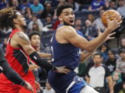 Minnesota Timberwolves center Karl-Anthony Towns, right, goes to the basket around Portland Trail Blazers forward Greg Brown III in the first quarter of an NBA basketball game Monday, March 7, 2022, in Minneapolis.