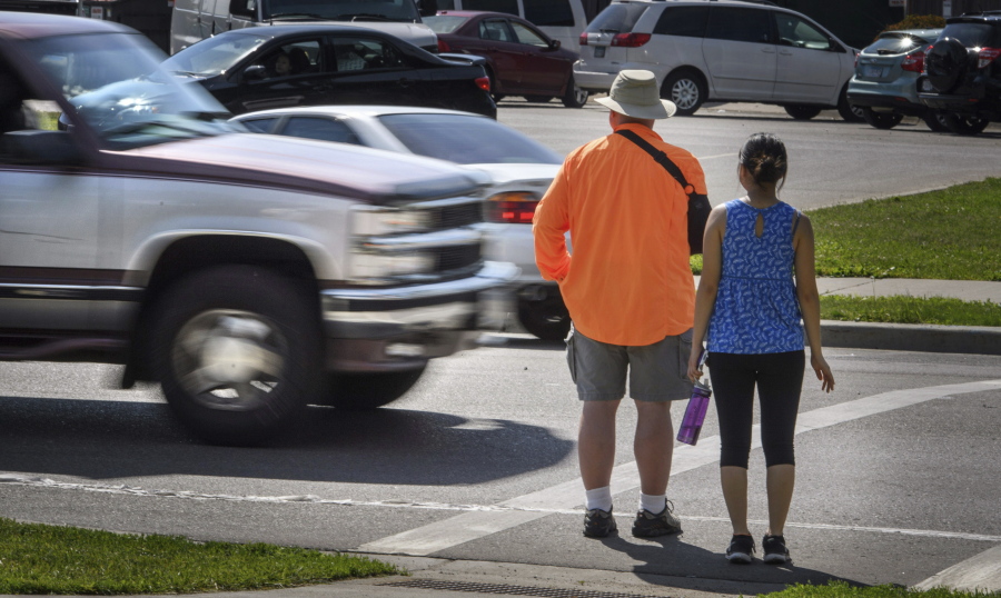 FILE - In this June 8, 2016, file photo, a maroon and silver truck drove, left, drives through the marked crosswalk in front of pedestrian volunteers Dave Passiuk and Nelsie Yang in St. Paul, Minn. Drivers of bigger vehicles such as pickup trucks and SUVs are more likely to hit pedestrians while making turns than drivers of cars, according to a new study. The research released Thursday, March 17, 2022, by the Insurance Institute for Highway Safety points to the increasing popularity of larger vehicles as a possible factor in rising pedestrian deaths on U.S. roads.