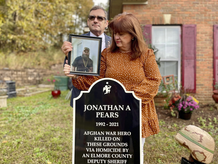 Andy and Mary Pears stand with a photo of their son by the memorial to him in the front yard of their home in Elmore County, Ala., on Nov. 5, 2021. Thirty-two-year-old Jonathan Pears was shot and killed by deputies on July 28, 2021. The couple said their son, a military veteran suffered PTSD and depression after returning from Afghanistan, and they called 911 seeking help for him during a mental health crisis. The Elmore County Sheriff's Office said Pears was holding a large knife and refused commands to drop it. His parents maintain deputies were a safe distance away and did not have to shoot their son.