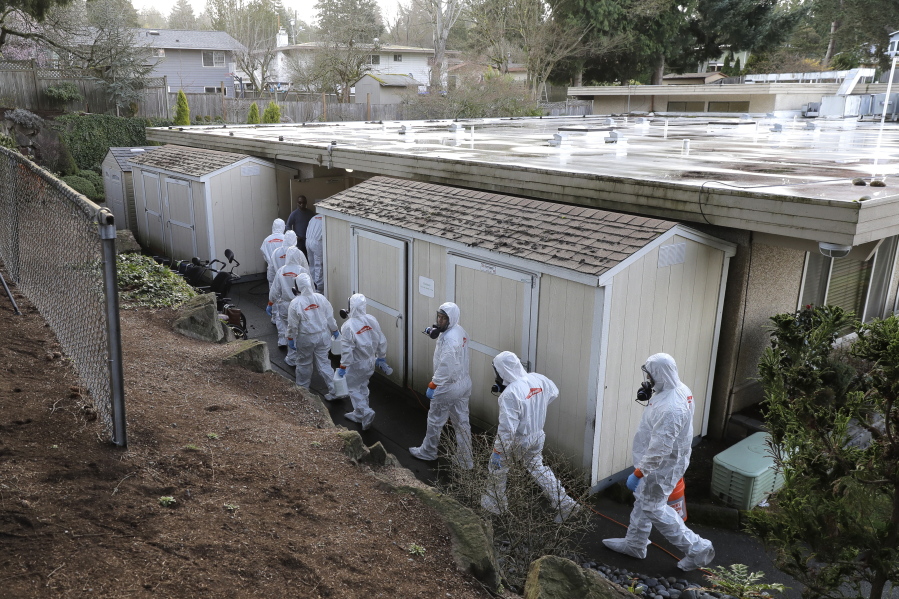 FILE - Workers from a Servpro disaster recovery team wearing protective suits and respirators enter the Life Care Center in Kirkland, Wash., to begin cleaning and disinfecting the facility, March 11, 2020, near Seattle. The nursing home was at the center of the coronavirus outbreak in Washington state. (AP Photo/Ted S.