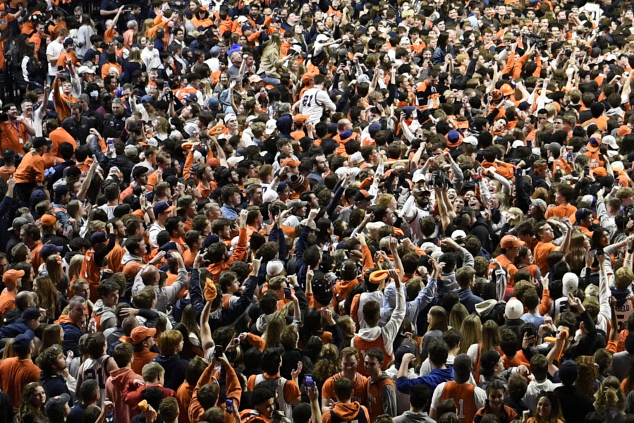 FILE - Fans storm the court at the conclusion of a college basketball game in Champaign, Ill., on Sunday, March 6, 2022. After about two months of falling COVID-19 cases, pandemic restrictions have been lifted across the U.S., and many people are taking off their masks and returning to indoor spaces.