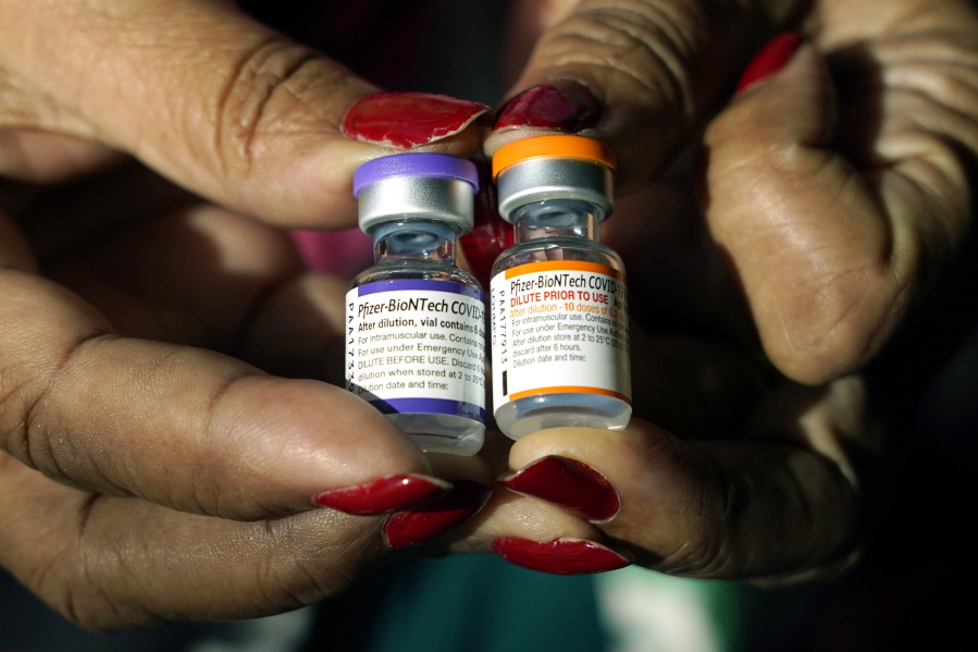 A nurse holds a vial of the Pfizer COVID-19 vaccine for children ages 5 - 11, right, and a vial of the vaccine for adults, which have different colored labels, at a vaccination station in Jackson, Miss., Tuesday, Feb. 8, 2022. Pfizer's COVID-19 vaccine gave children 5 and older strong protection against hospitalization and death even during the omicron surge that hit youngsters especially hard, according to new data from the Centers for Disease Control and Prevention released on Tuesday, March 1, 2022. (AP Photo/Rogelio V.