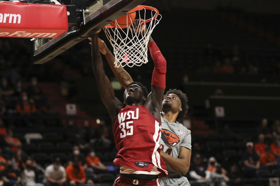 Washington State forward Mouhamed Gueye dunks in front of Oregon State forward Ahmad Rand during the second half of an NCAA college basketball game on Monday, Feb. 28, 2022, in Corvallis, Ore. Washington State won 103-97.