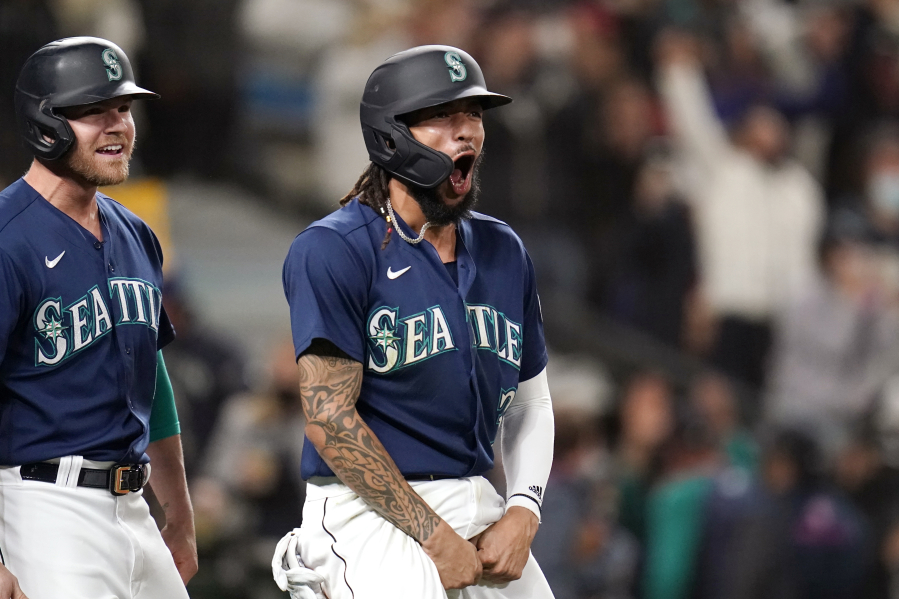Seattle Mariners' J.P. Crawford, right, celebrates with Jake Bauers after both scored against the Los Angeles Angels in the eighth inning of a baseball game Saturday, Oct. 2, 2021, in Seattle.