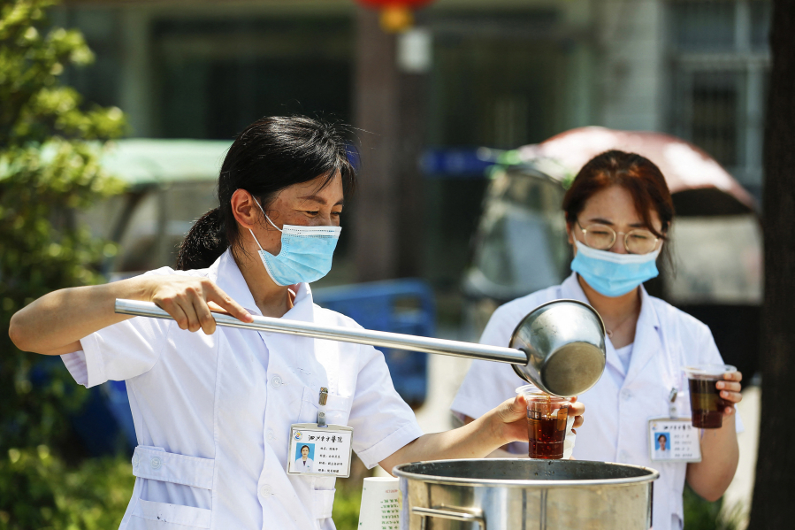 A staff member distributes free traditional Chinese medicine amid a rise in COVID-19 coronavirus cases across the country in Sihong, Suqian city, in China's eastern Jiangsu province, on Aug. 1, 2021.