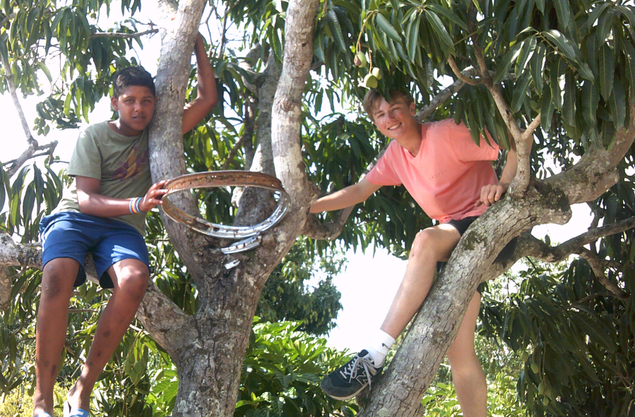 Columbia River High School sophomore Peter Lubisich, right, sits in a mango tree with a teenager from El Rodeo, Dominican Republic. Before Courts For Kids built an outdoor sports court, the town's youth played basketball on a makeshift hoop nailed to the tree.