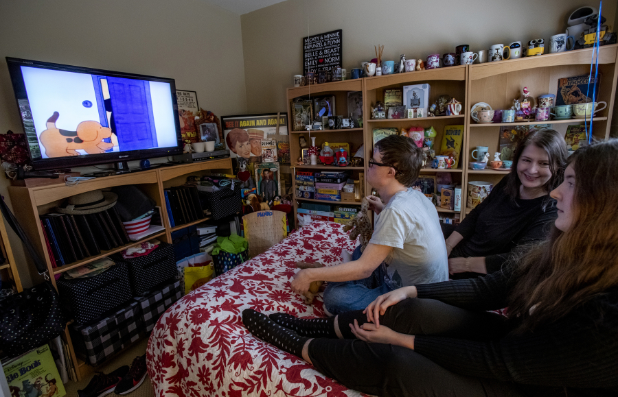 Emily Brooke Holth (middle) and her daughter Kaia, 24, watch a DVR movie with Kaia's twin brother Ry who has Down's Syndrome, on March 31, 2022, in Monrovia, California.
