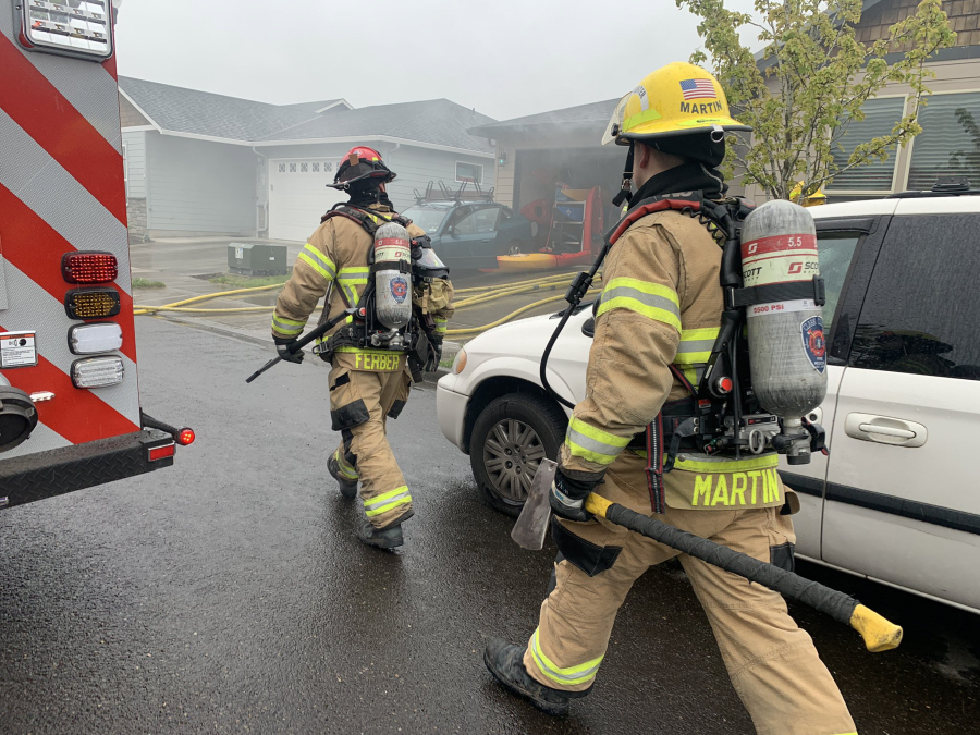 Firefighters extinguish a Battle Ground house fire Monday. A family of five was displaced and one person was taken to an area hospital to be treated for minor burns and smoke inhalation.
