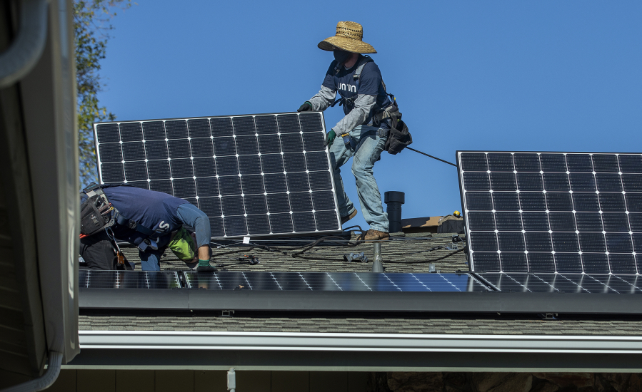 Workers install solar panels on the roof of a home in Granada Hills, California.
