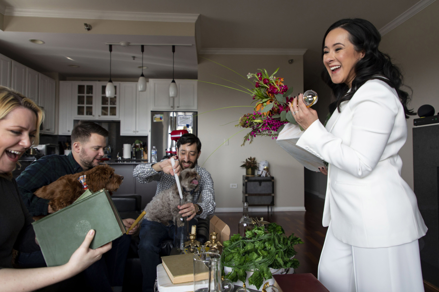 Rachel Ambrozewski, right, and Evan Cooperman, second from right, look over their planned decorations April 10 with bridesmaid Ryann Rase, left, and groomsman Chris Robinson at their Chicago home. The couple were forced to cancel their wedding plans multiple times during the pandemic and have rescheduled their celebration for June.
