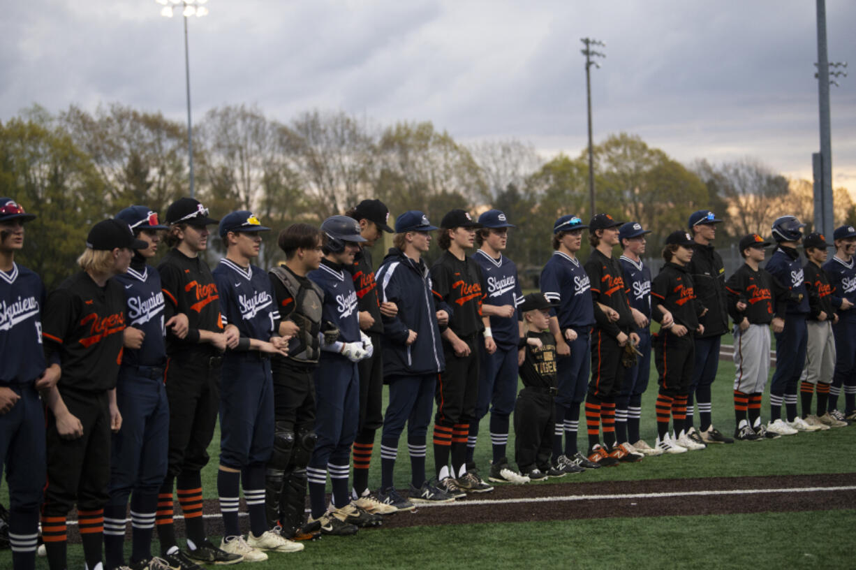 Players from the Battle Ground and Skyview baseball teams stand arm in arm in a show against discrimination prior to their game at Propstra Stadium on Monday.