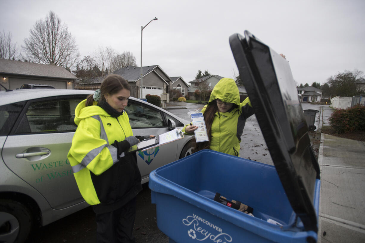 Jerin Dinkins, left, and Gina Evans, recycling specialists with Waste Connections of Washington, look for items that cannot be recycled while on their route in northeast Vancouver in January 2020.
