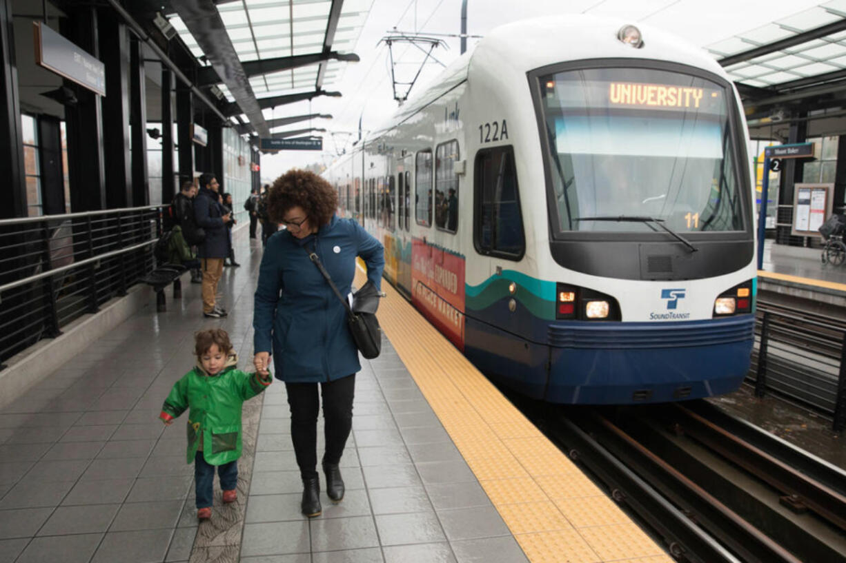 In this November 22, 2017 file photo, then Seattle city councilmember Kirsten Harris-Talley, with two-year-old son Malcolm, prepares to board a light rail train at the Mt. Baker station, for a short trip to Beacon Hill where her son attends a local pre-school. Washington youth under 18 will soon ride transit for free as part of a new transportation package. (Matt M.