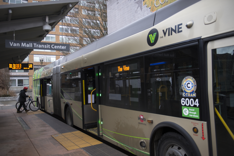 A cyclist boards a C-Tran Vine bus at the Turtle Place Transit Center in downtown Vancouver in February 2021.